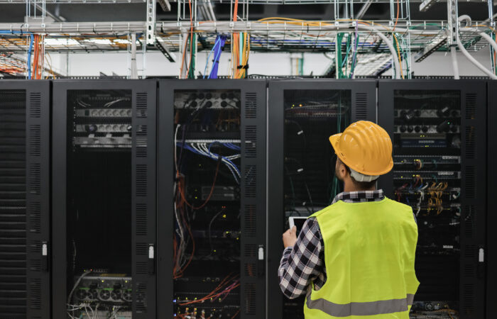 Young technician man working with tablet inside big data center Data Center